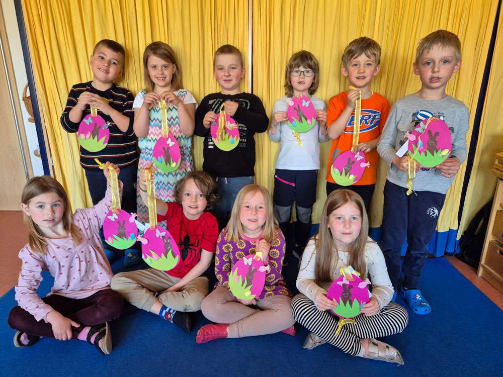 Es sind 10 Kinder der Kitagruppe "Sonnenkinder" der Integrativen Kindertagesstätte der Lebenshilfe Bützow zu sehen. Sie zeigen ihre aus Papier gebastelten pinken Ostereier stolz in die Kamera.